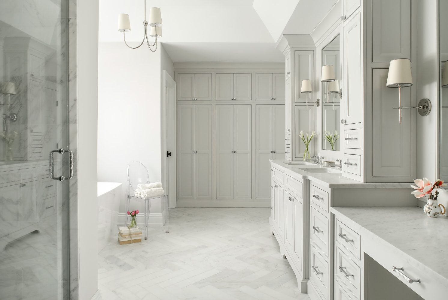 Extensive built-in cabinetry, vanity, and makeup table in white marble bathroom.